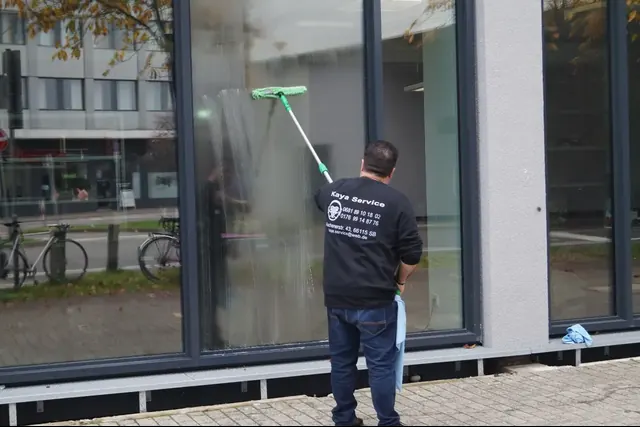 Mitarbeiter reinigt eine große Glasfront